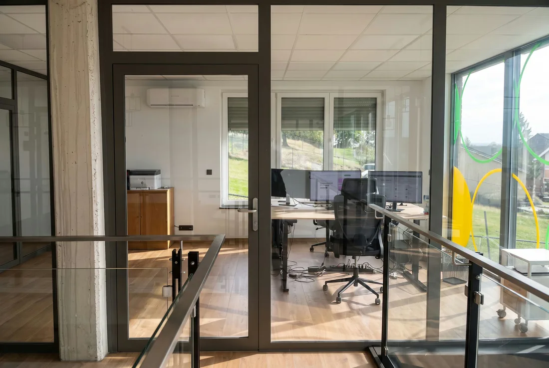 Blick auf das Büro von Bits & Bots in Kelmis, Arbeitsplätze hinter den Glastüren